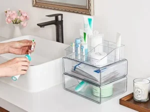 Clear acrylic drawers organizing skincare and toothbrushes on bathroom countertop
