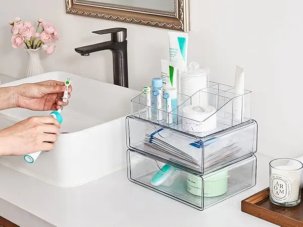 Clear acrylic drawers organizing skincare and toothbrushes on bathroom countertop