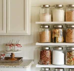 Floating shelf above kitchen counter holding glass jars in a tiny house