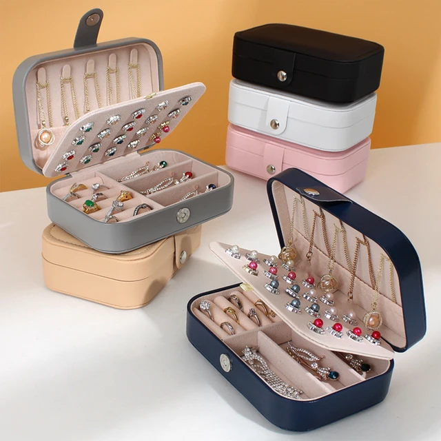 Multiple styles of travel jewelry organizer boxes displayed near open luggage
