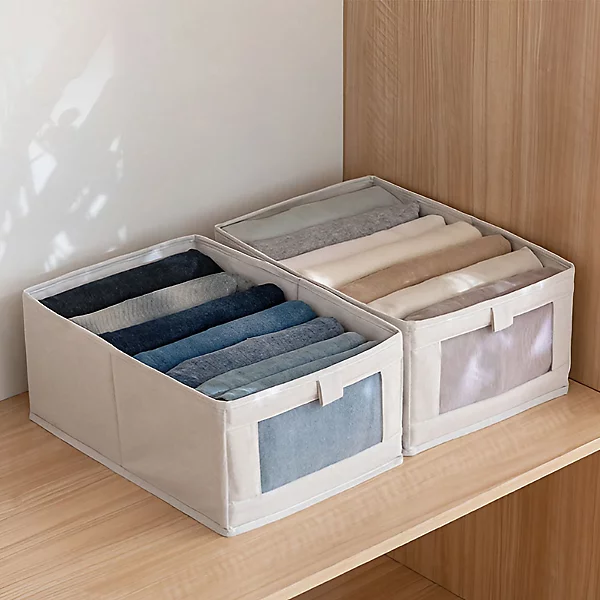 Rolled jeans neatly arranged inside fabric storage boxes