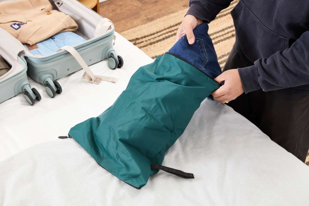 Traveler packing dirty laundry into a travel bag inside hotel room
